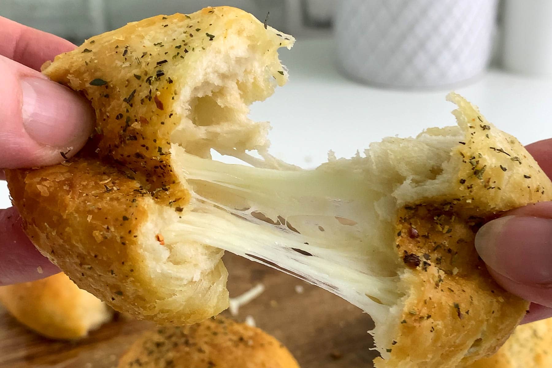 Pulling apart a garlic cheese ball filled with stringy mozzarella cheese.