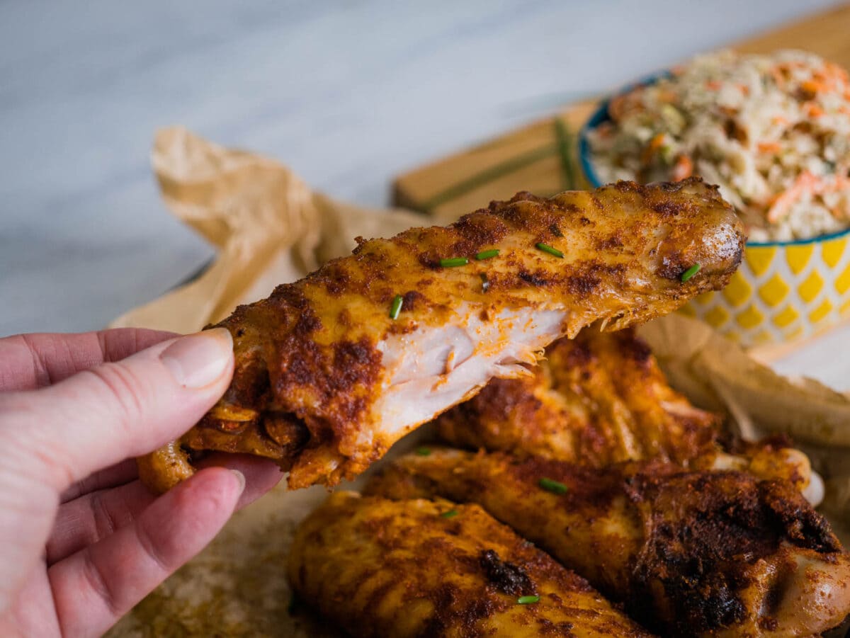 holding an air fryer turkey wing coated in spices