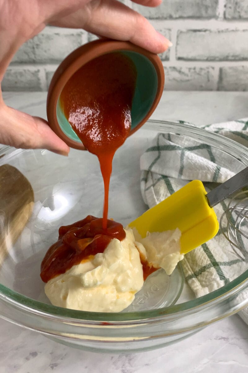 adding ketchup to the sauce