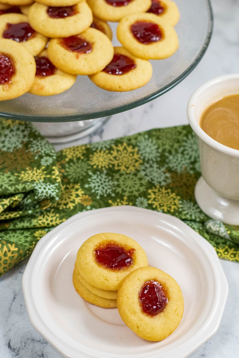 thumbprint cookies on a plate in front of coffee cup