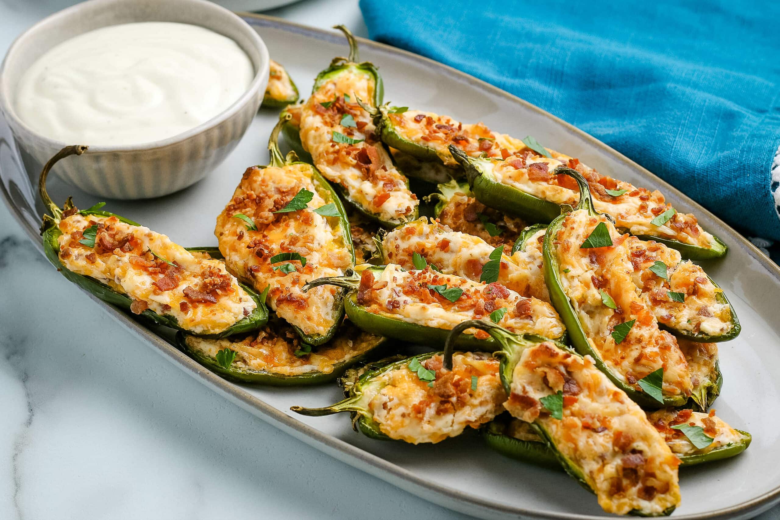 Jalapeño Poppers on a platter with a bowl of dipping sauce.
