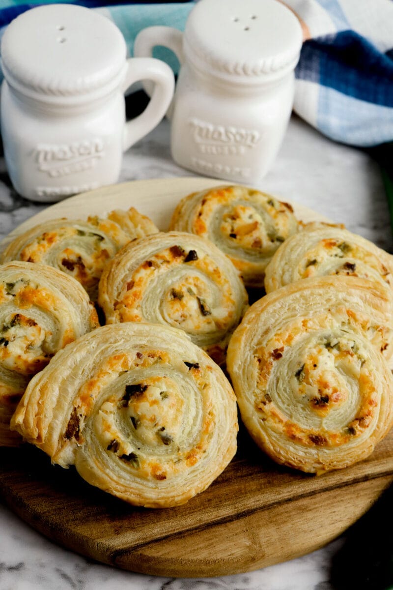 jalapeno popper pinwheels on a cutting board with salt and pepper in the background