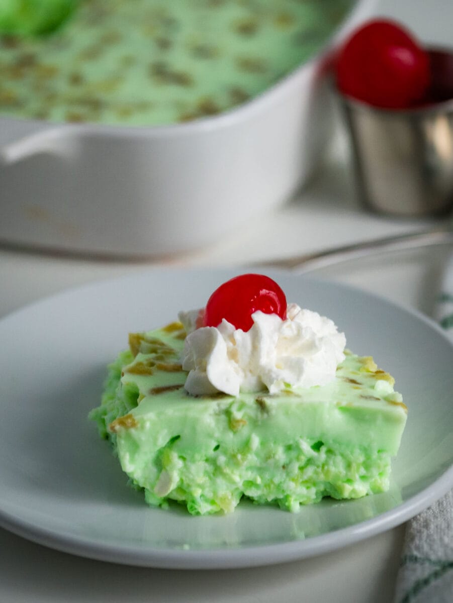 green jello salad topped with whipped cream and a cherry.
