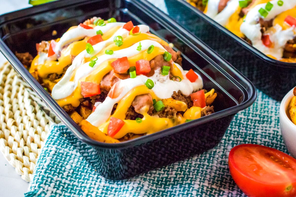 container with nacho fries topped with cheese and veggies