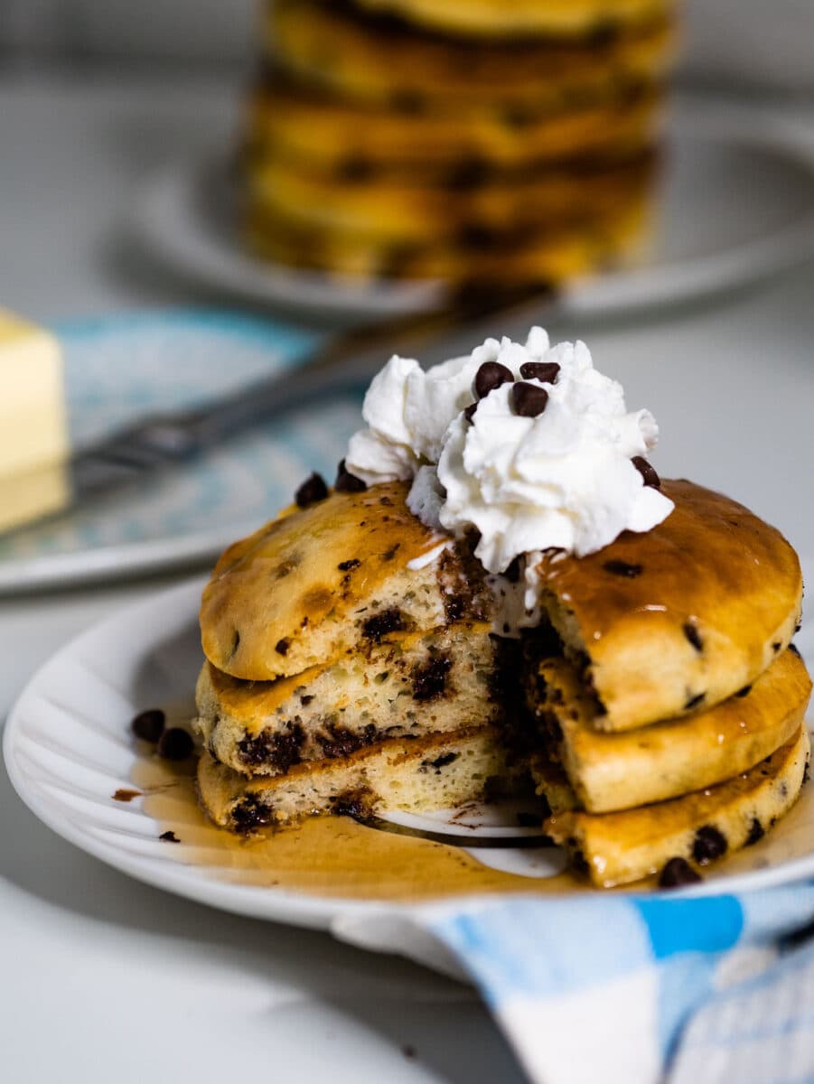 stack of chocolate chip pancakes with whipped cream.