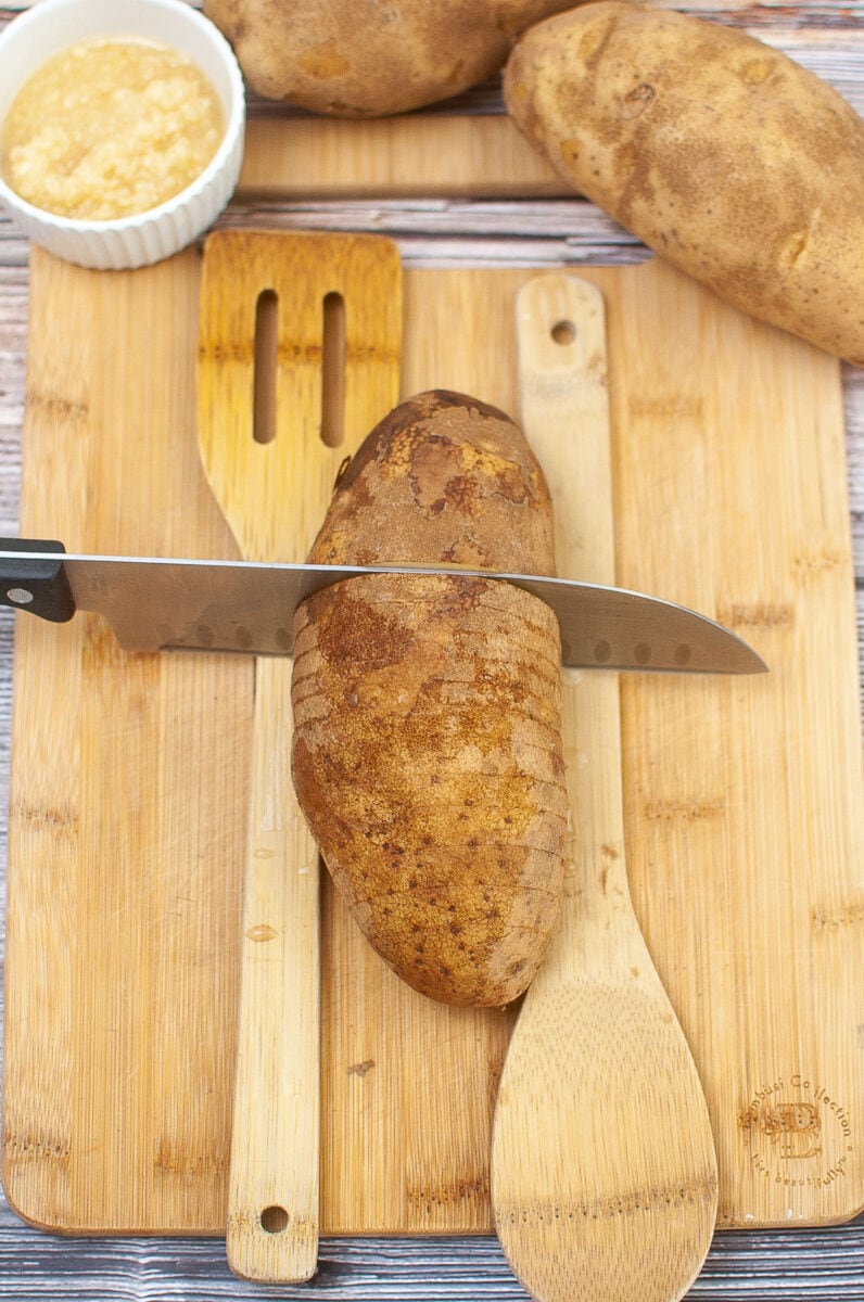 slicing the potato for hasselback potatoes.