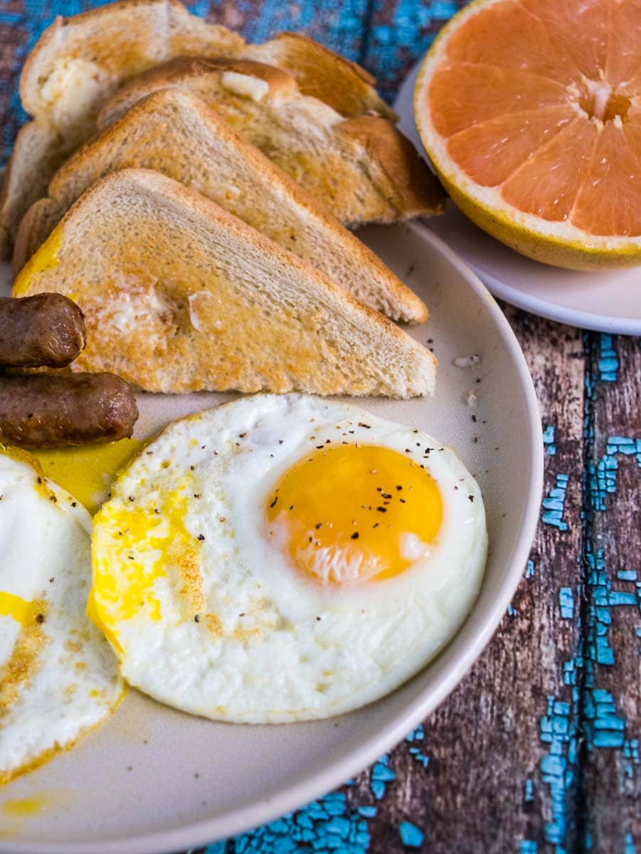 plate with fried egg, toast and sausage.