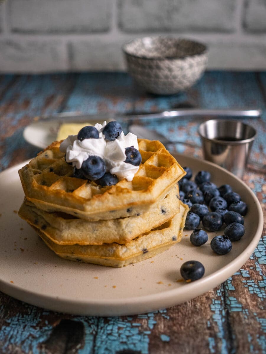 stack of blueberry waffles with whipped cream.