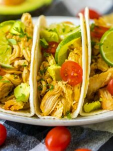 closeup of slow cooker chicken tacos with tomatoes and lime.