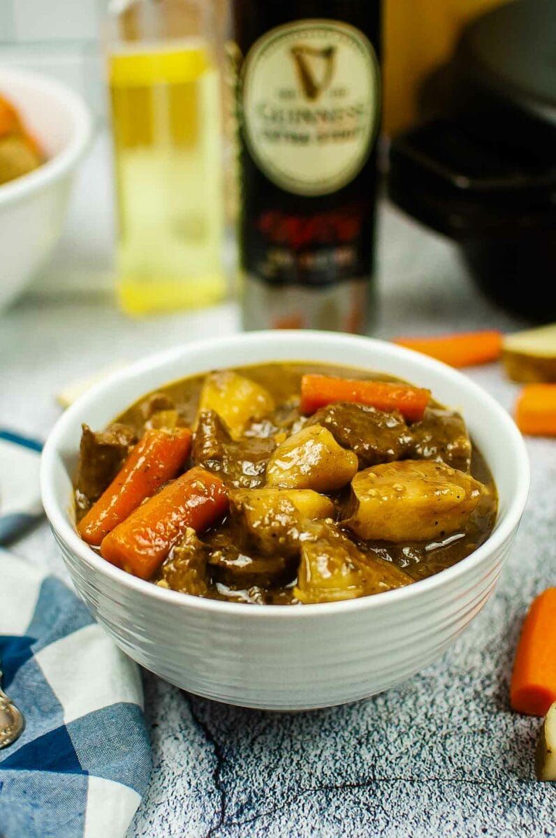Irish beef stew with bottle of Guinness in the background.