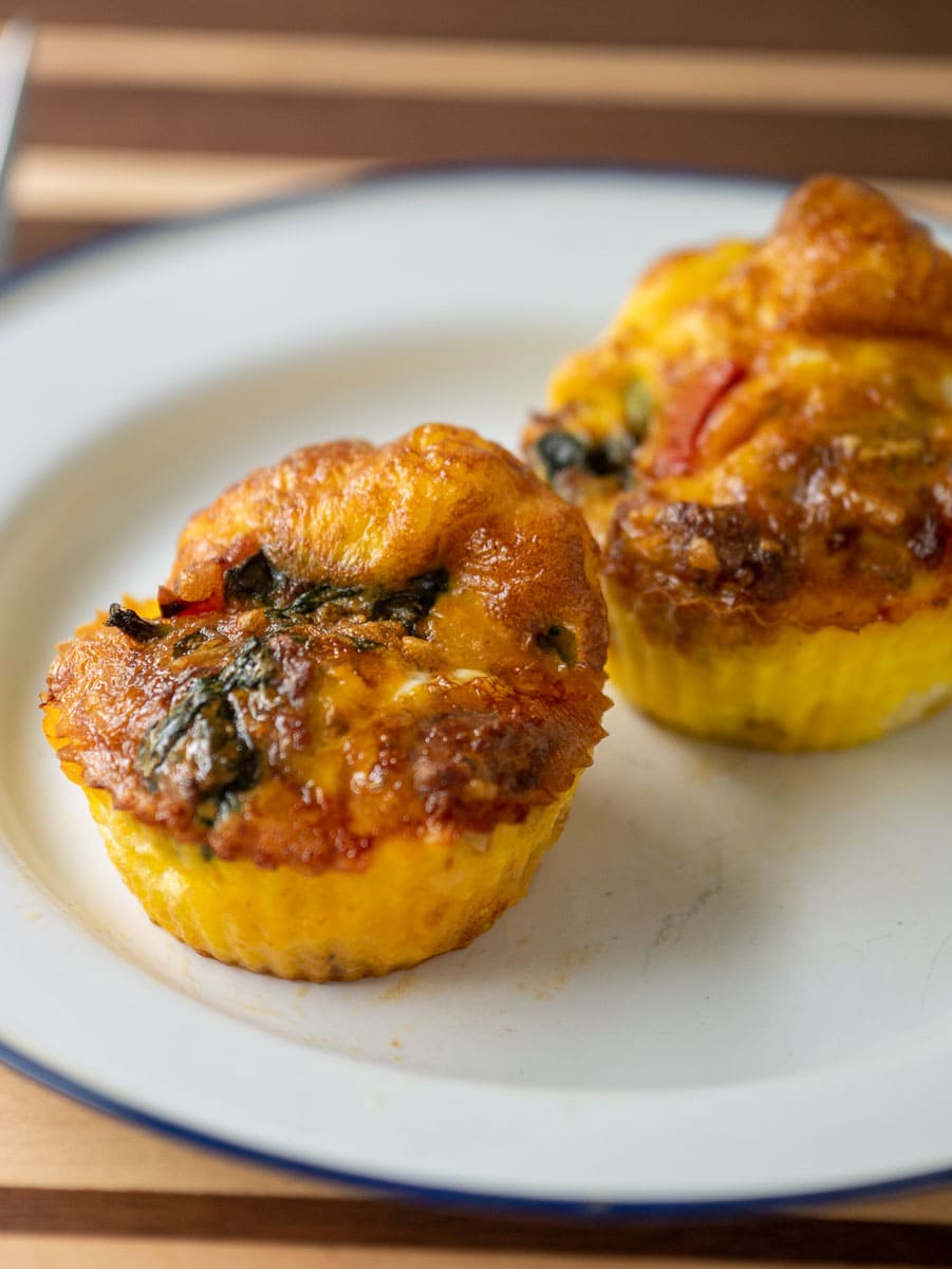 Muffin cups made with egg, sausage and peppers on a plate.