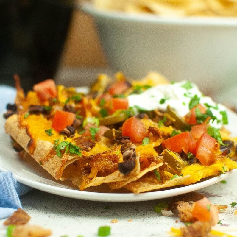 side view of a plate of air fryer nachos loaded with toppings.