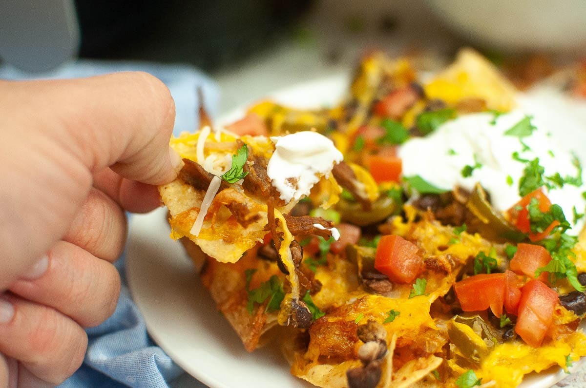scooping up air fryer nachos with a chip.