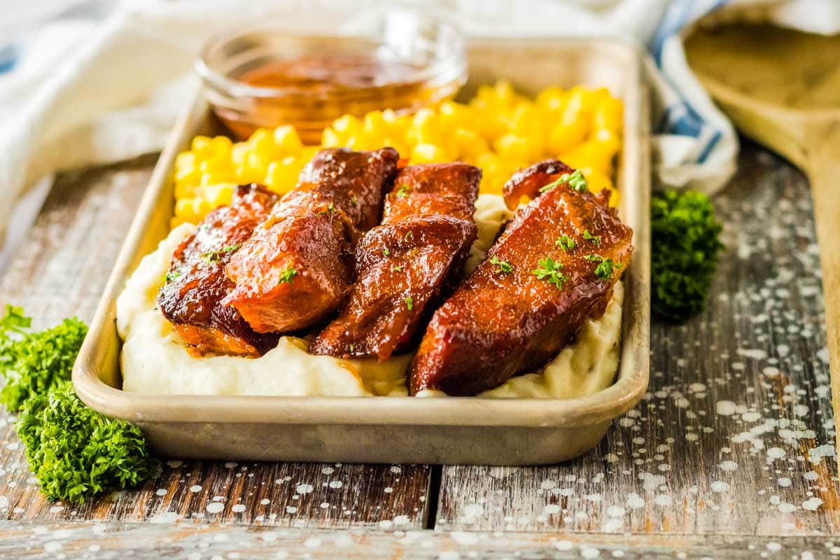 ribs on a tray with corn and mashed potatoes.