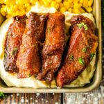 top view of slow cooker ribs with corn and mashed potatoes on a tray.
