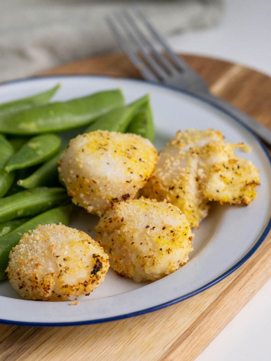 breaded air fryer scallops on a plate with snap peas.