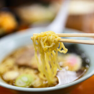 Ramen noodle soup on chopsticks.