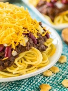 Side view of Cincinnati chili on spaghetti topped with cheese and onions.