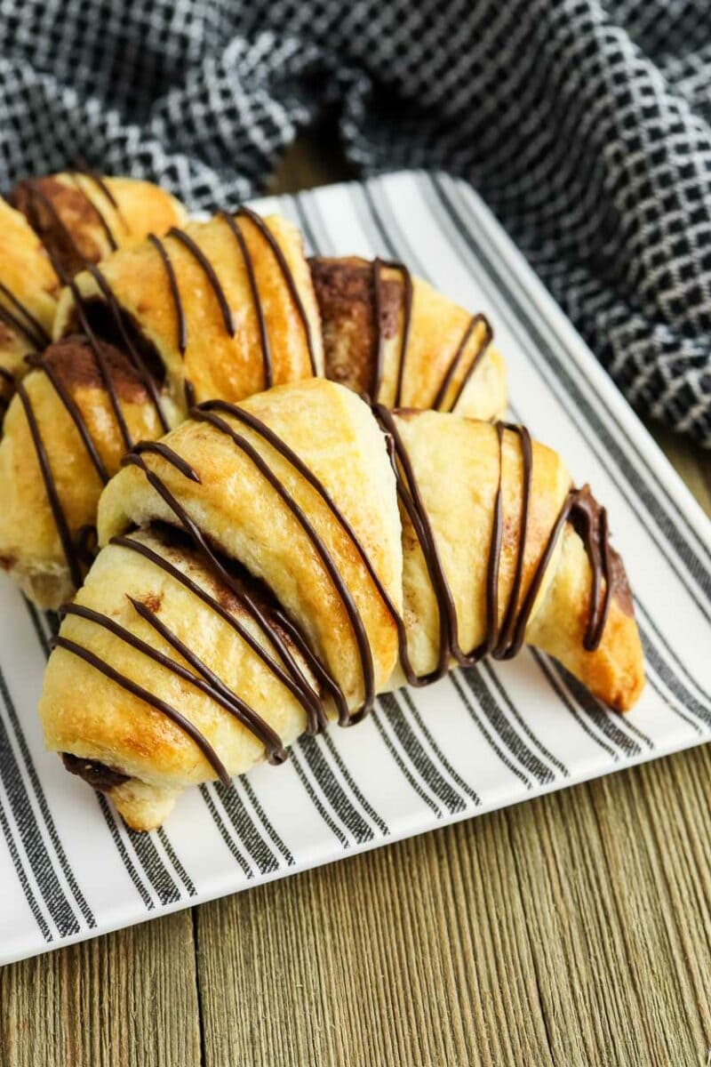Closeup photo of nutella stuffed crescent rolls on a plate drizzled with chocolate.
