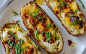 potatoes on a plate with cheese, bacon and chives
