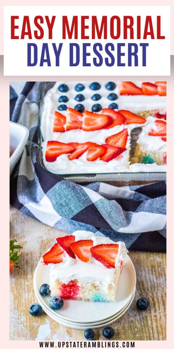 A slice of 4th of July poke cake topped with whipped cream and strawberries sits on a plate next to blueberries; the rest of the festive cake is in a pan in the background.