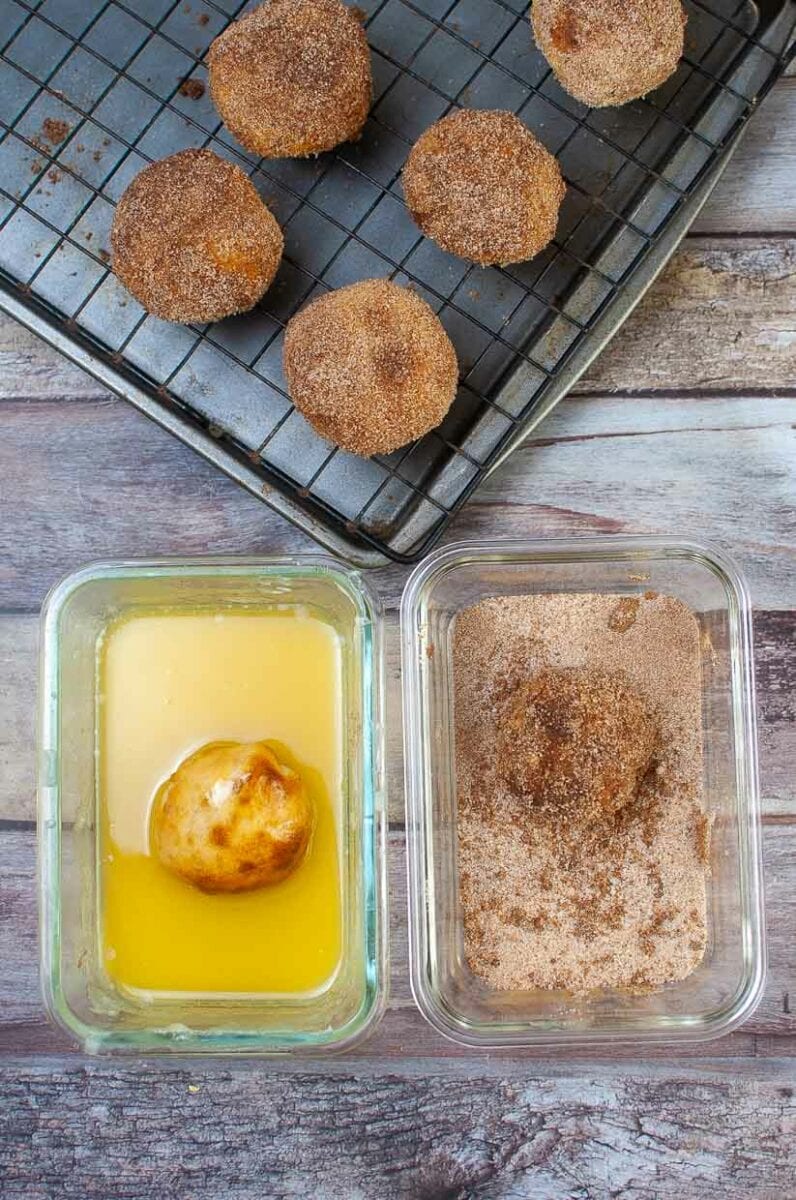 Dipping the cooked apple pie bombs in butter and cinnamon sugar.