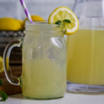 Mason jar glass with copycat Chick fil a lemonade in front of a bowl of lemons and a pitcher.