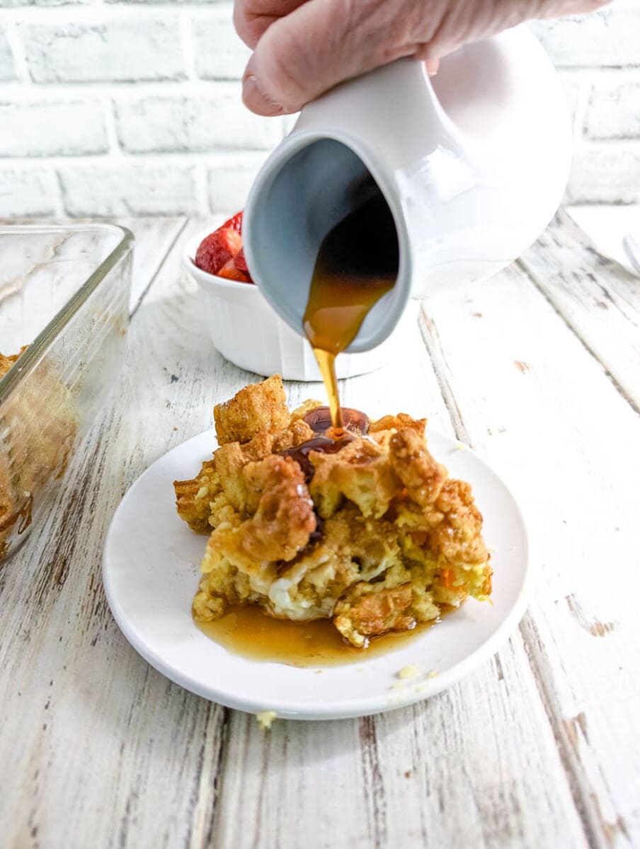 Pouring maple syrup over the chicken and waffle casserole.