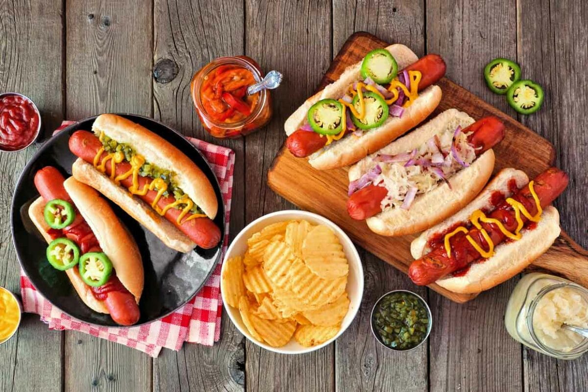 Top view of hot dogs on a table with various toppings.