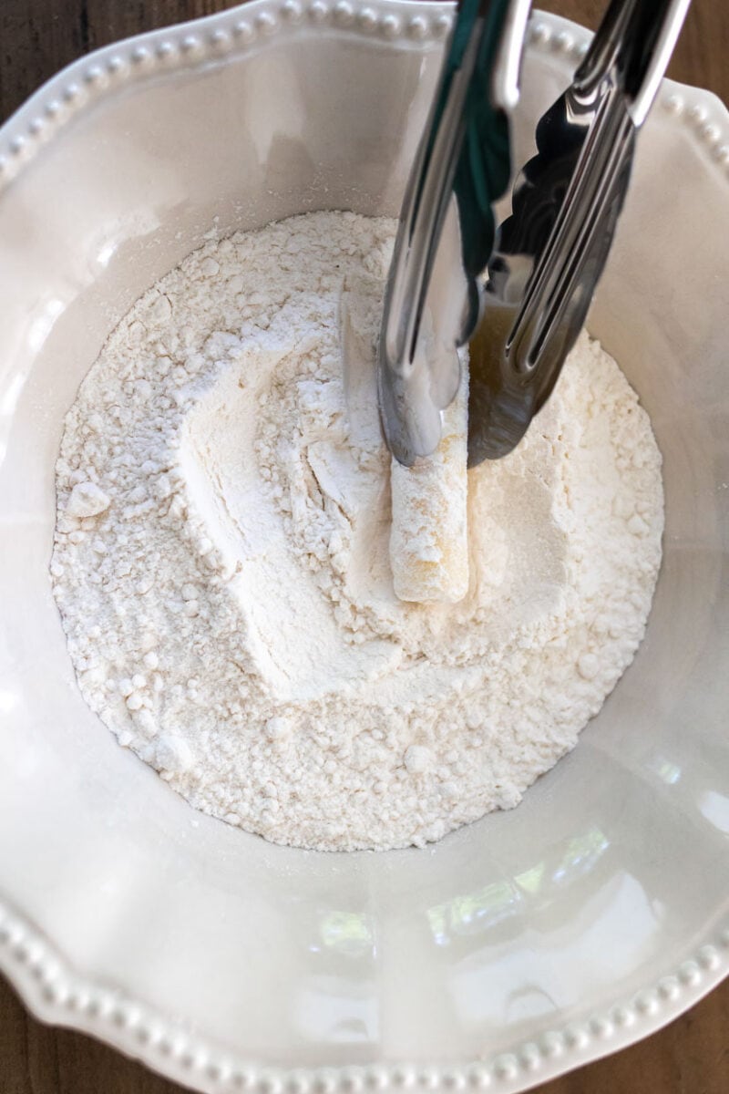 Dip the mozzarella stick in flour.