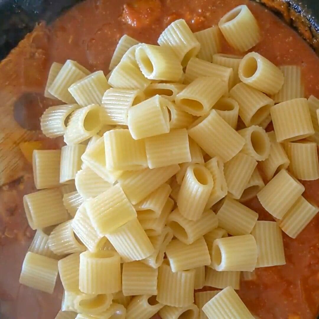 adding pasta to a skillet of sauce