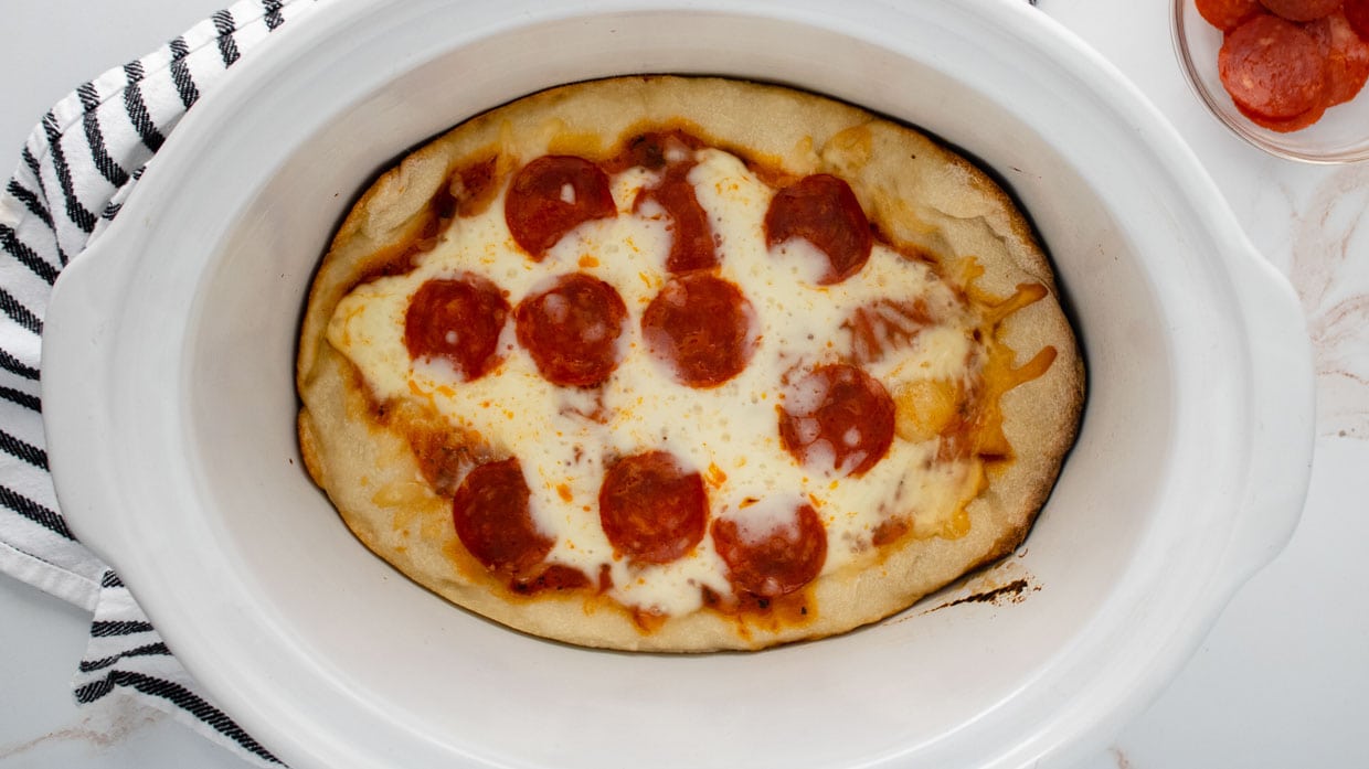 Pepperoni pizza in a white crock pot after cooking.