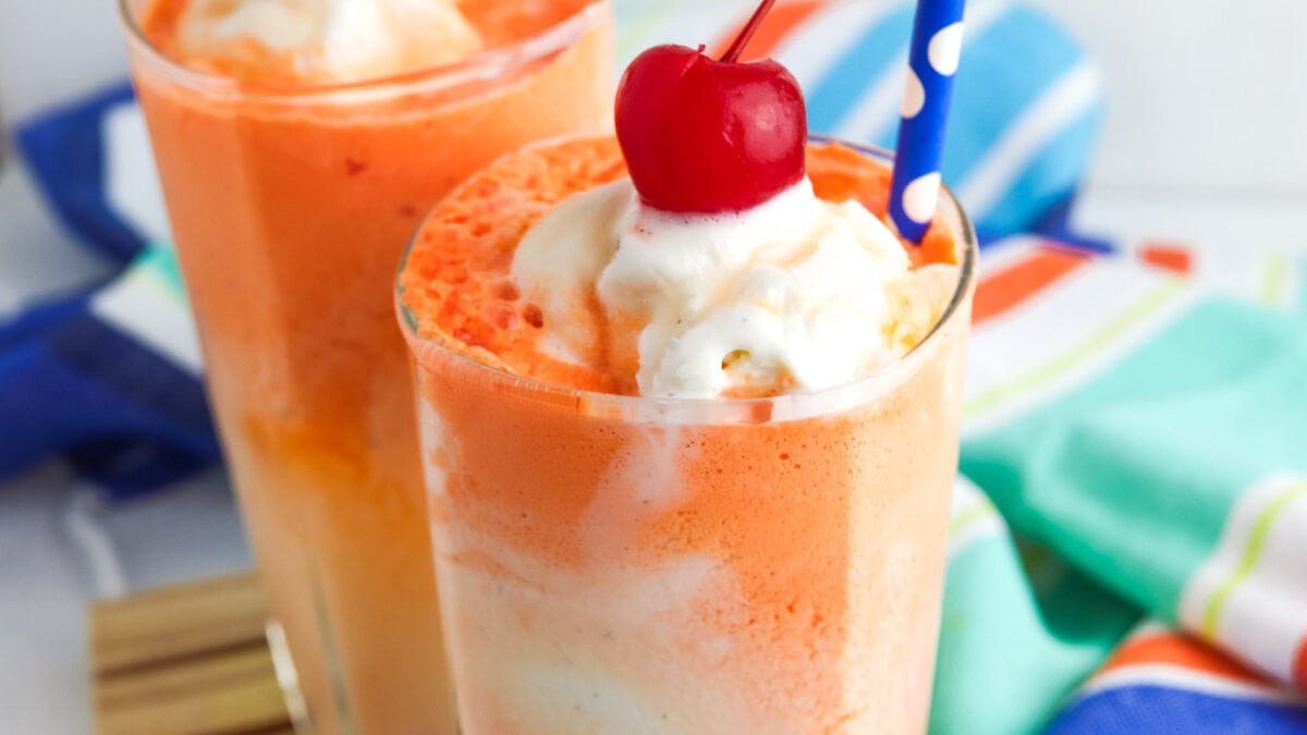 Orange creamsicle float topped with whipped cream and a cherry.
