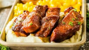 ribs on a tray with corn and mashed potatoes.