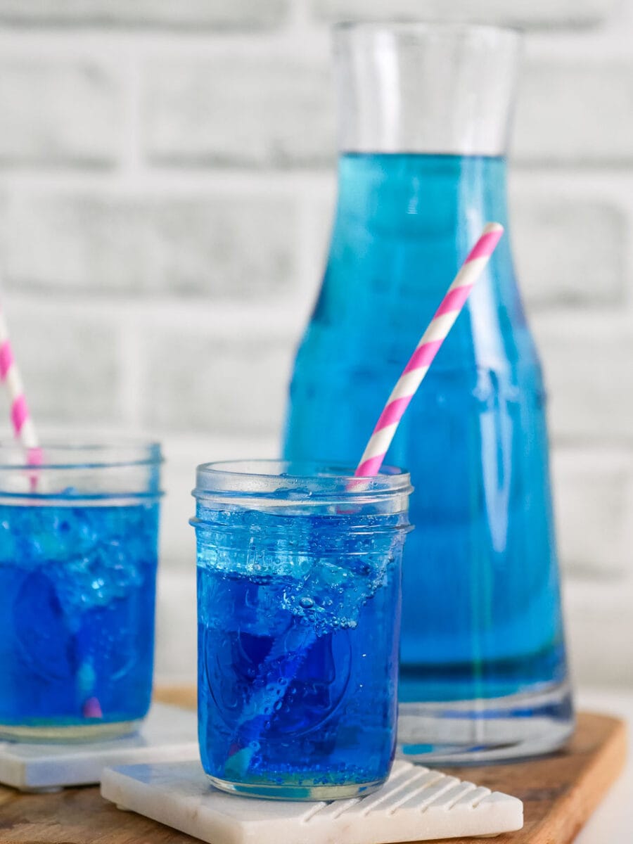 Two mason jars with bright blue drink and pink straws.