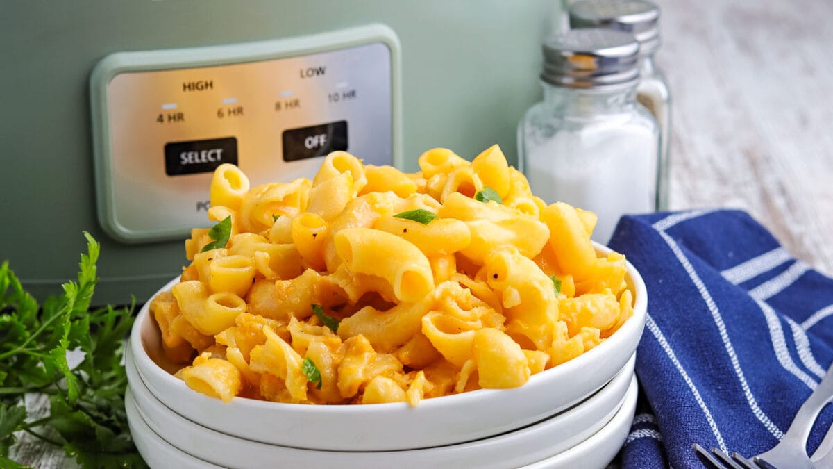 Bowl of slow cooker mac and cheese in front of the crock pot.