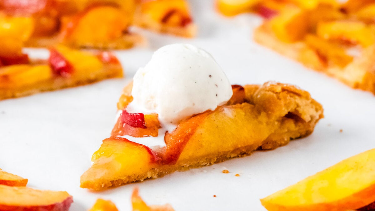 Slice of peach crostata topped with ice cream.