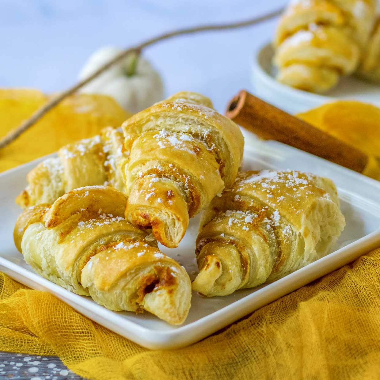 Pumpkin pie crescent rolls on a white plate with yellow fabric.