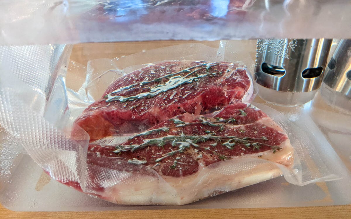 New york strip steak with thyme in a sous vide water bath.