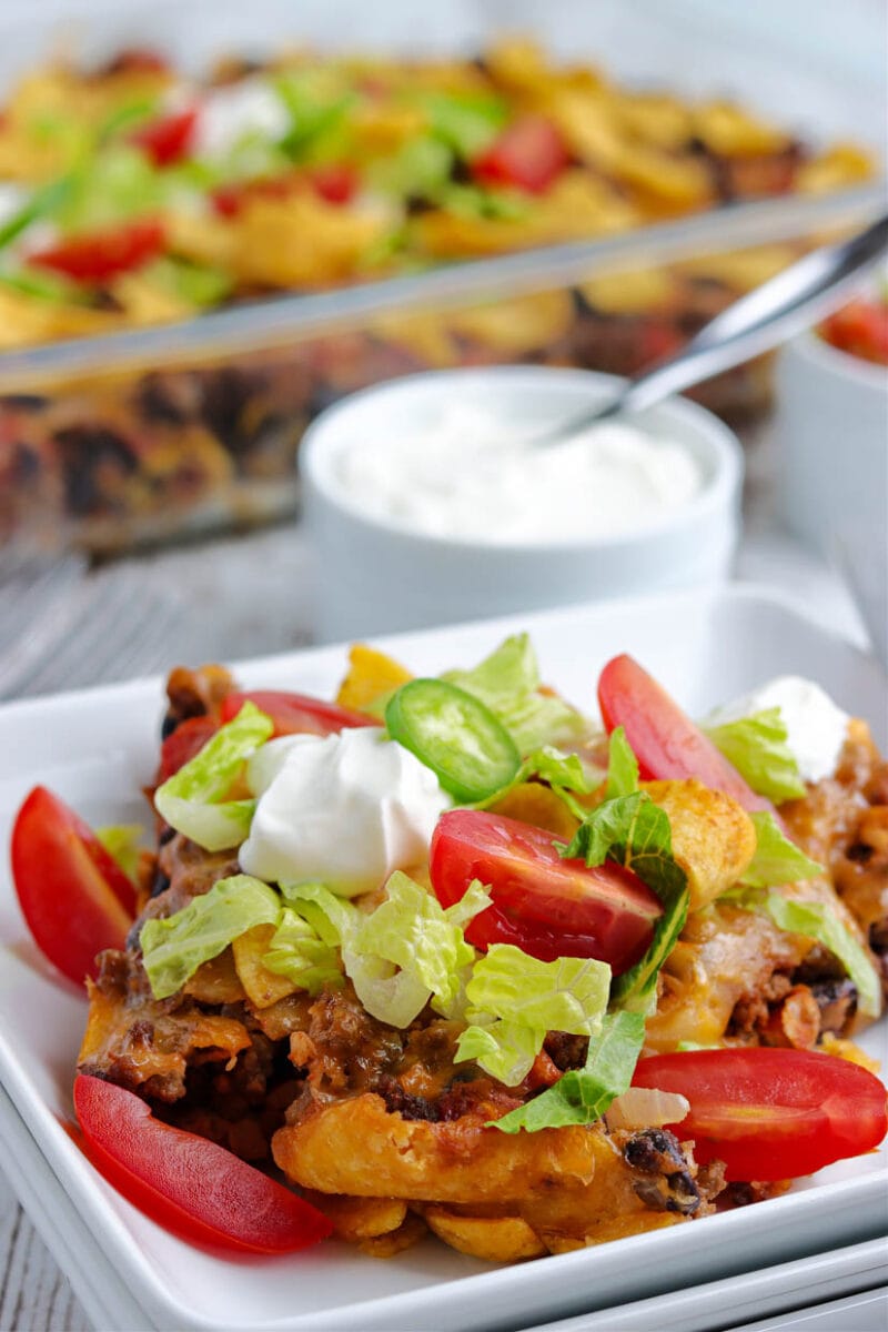 Walking taco casserole on a plate with toppings.