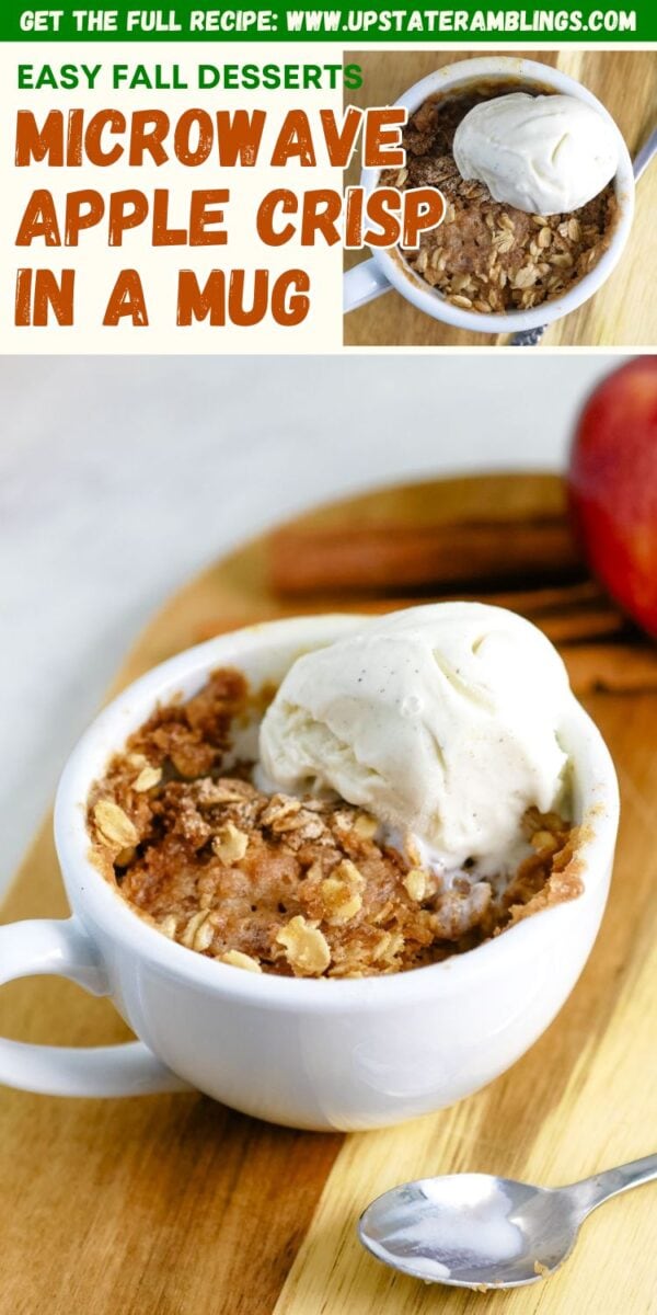 A white mug filled with apple crisp in a mug, topped with a scoop of vanilla ice cream, placed on a wooden board with a spoon beside it.