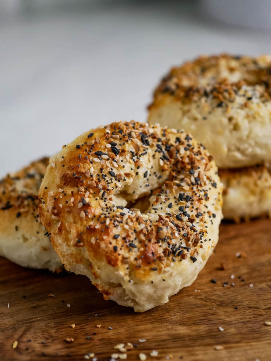 Bagels with sesame seeds on a wooden cutting board.