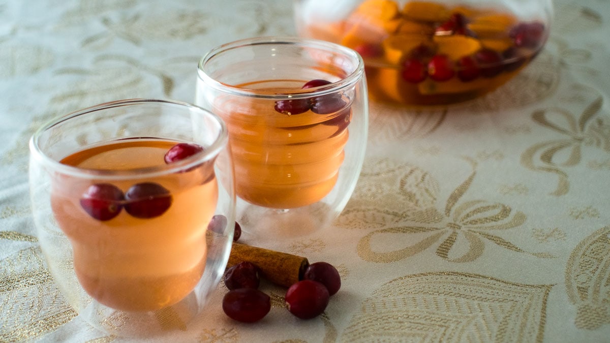 Two glasses of cranberry sangria with sugared cranberries on a table.