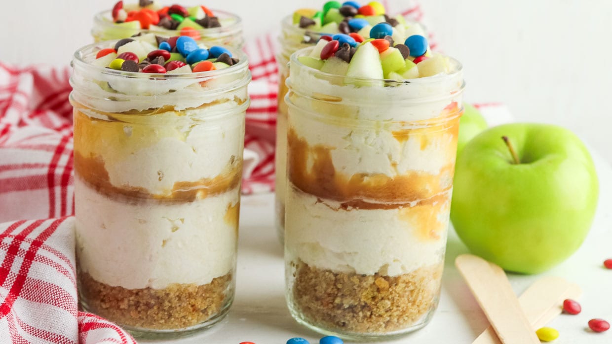 Jars of no bake cheesecake with caramel and candy.