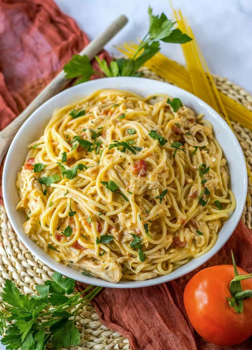 A bowl of spaghetti with chicken and tomatoes.
