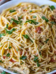 A bowl of spaghetti with chicken and tomatoes.