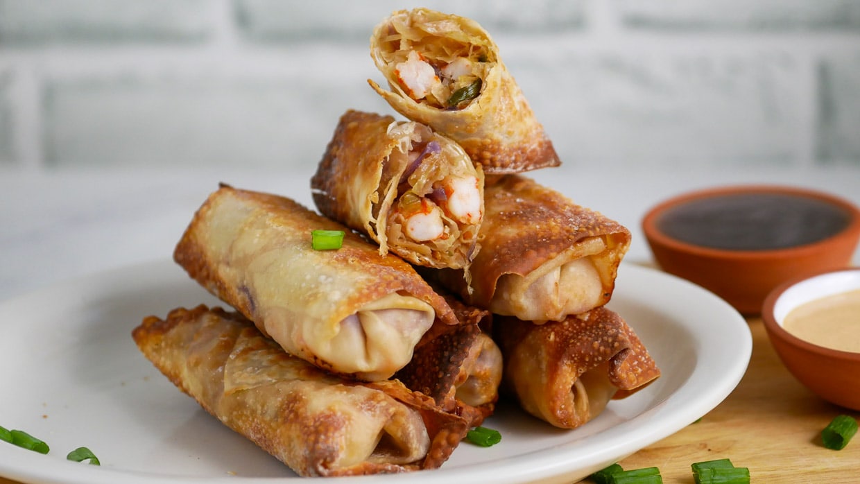 Egg rolls on a plate with dipping sauce.