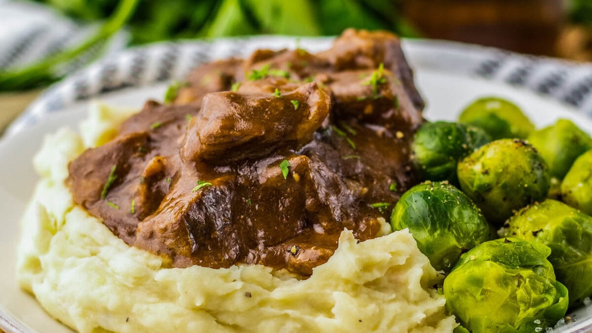 Beef tips with mashed potatoes and brussels sprouts.
