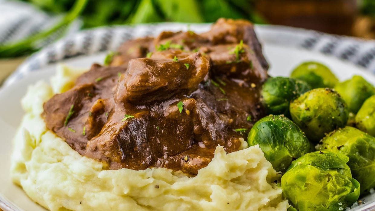 Beef tips with mashed potatoes and brussels sprouts.
