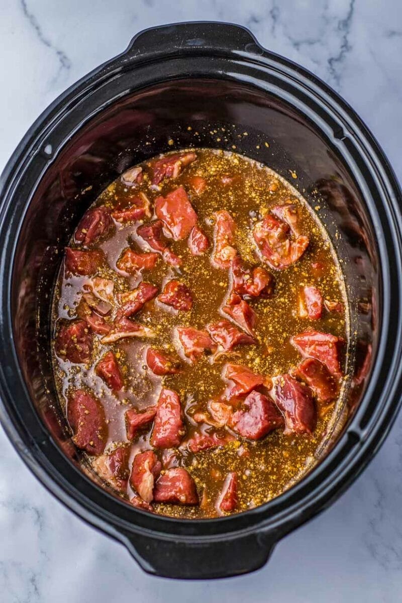 A crock pot filled with meat and sauce.